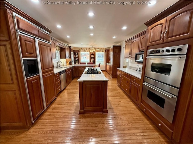 kitchen with sink, a kitchen island, appliances with stainless steel finishes, light hardwood / wood-style floors, and kitchen peninsula