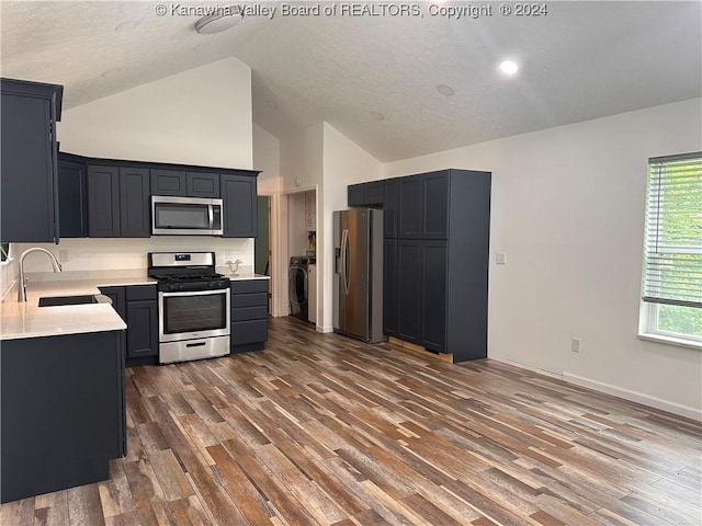 kitchen with sink, dark hardwood / wood-style flooring, high vaulted ceiling, washer / dryer, and appliances with stainless steel finishes