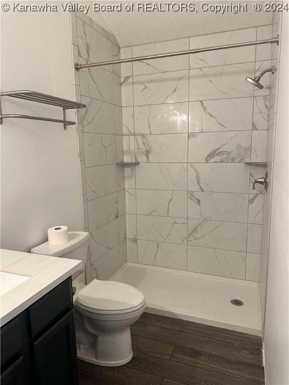 bathroom with tiled shower, vanity, hardwood / wood-style flooring, and toilet