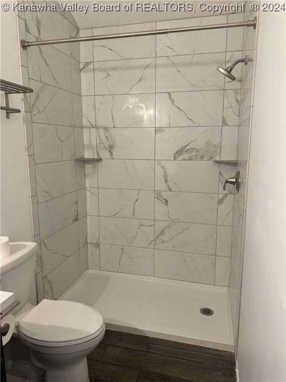 bathroom with a tile shower, hardwood / wood-style floors, vanity, and toilet