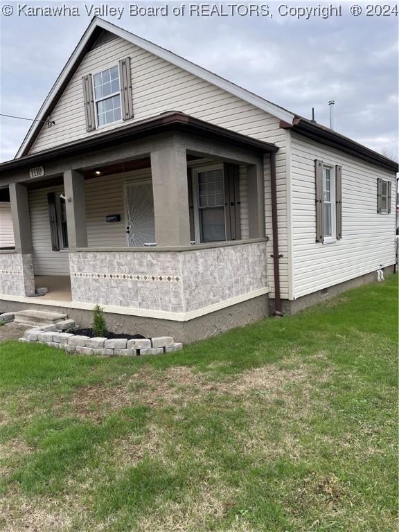 view of side of property featuring a lawn and covered porch