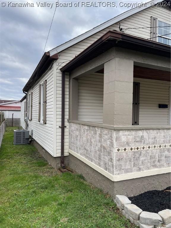 view of home's exterior with cooling unit and a lawn