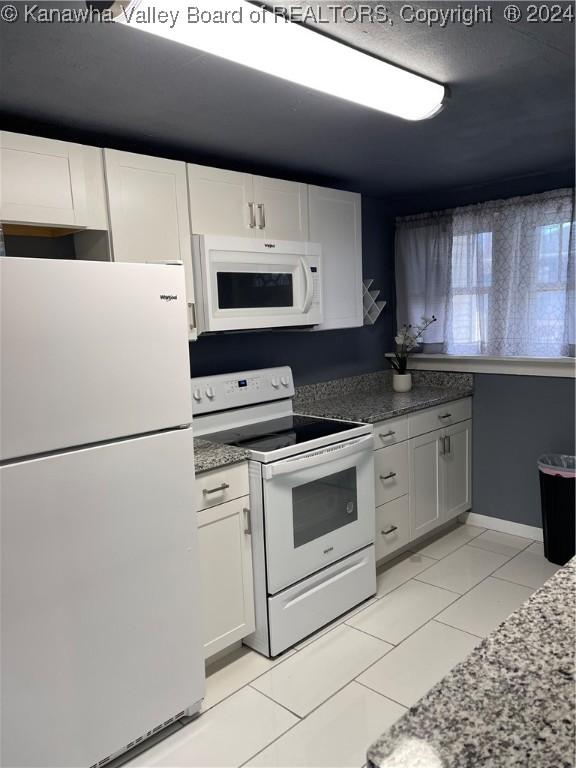 kitchen featuring white cabinets, light tile patterned floors, and white appliances