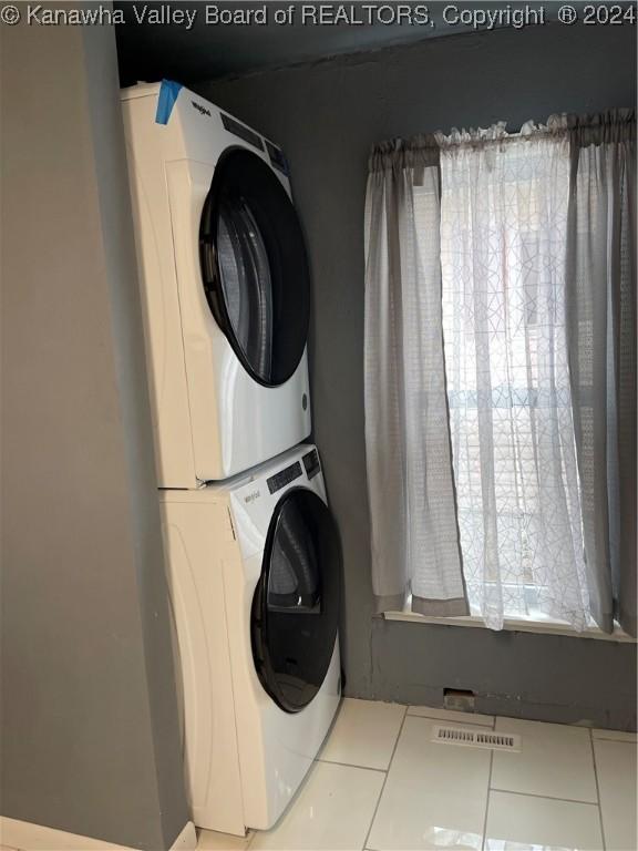 washroom with stacked washer / dryer, plenty of natural light, and light tile patterned flooring