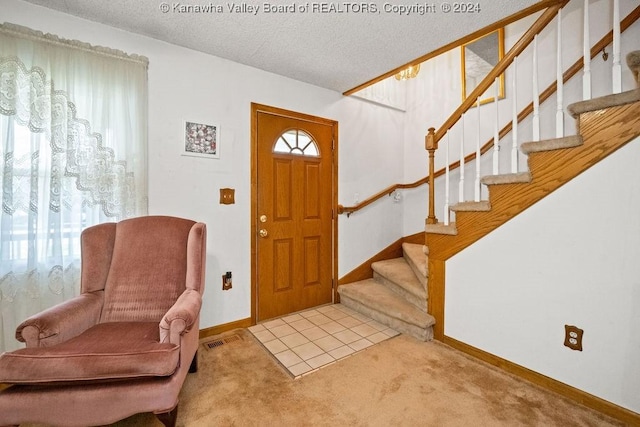 foyer with light carpet and a textured ceiling