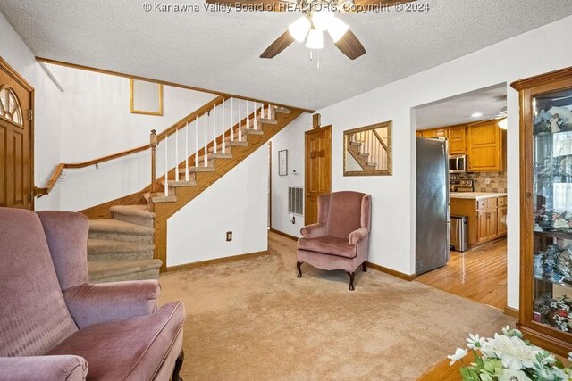 living room with a textured ceiling, light hardwood / wood-style floors, and ceiling fan