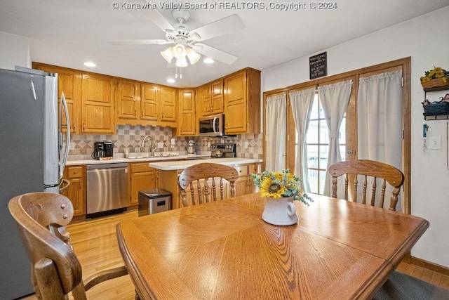 dining space with ceiling fan, sink, and light wood-type flooring