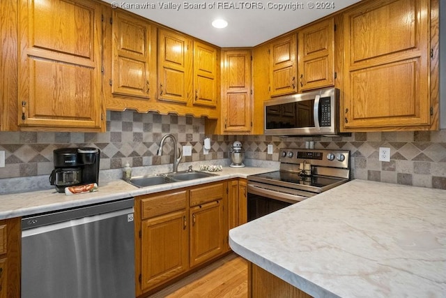 kitchen featuring sink, light wood-type flooring, stainless steel appliances, and tasteful backsplash