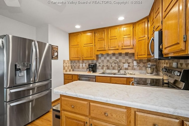 kitchen featuring decorative backsplash, sink, light wood-type flooring, and appliances with stainless steel finishes