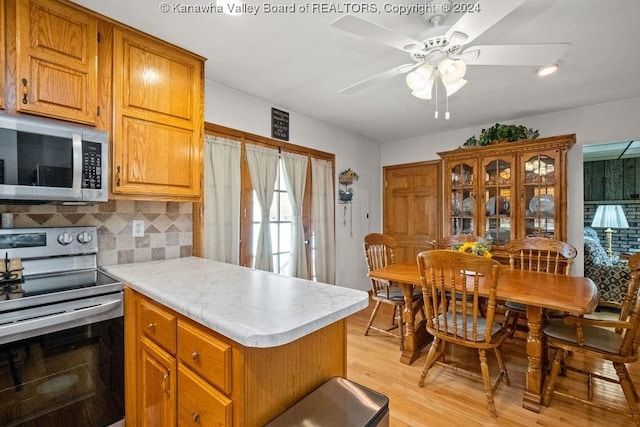 kitchen with backsplash, ceiling fan, stainless steel appliances, and light hardwood / wood-style flooring