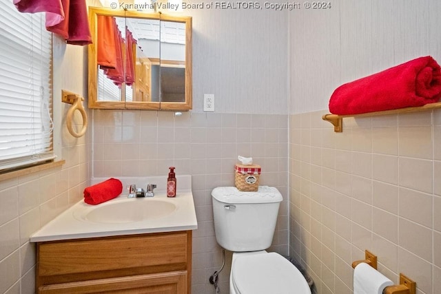 bathroom with vanity, toilet, and tile walls