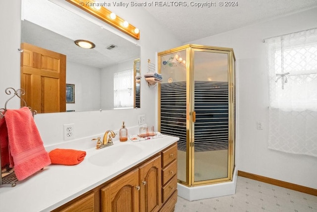 bathroom featuring plenty of natural light, vanity, a shower with shower door, and a textured ceiling