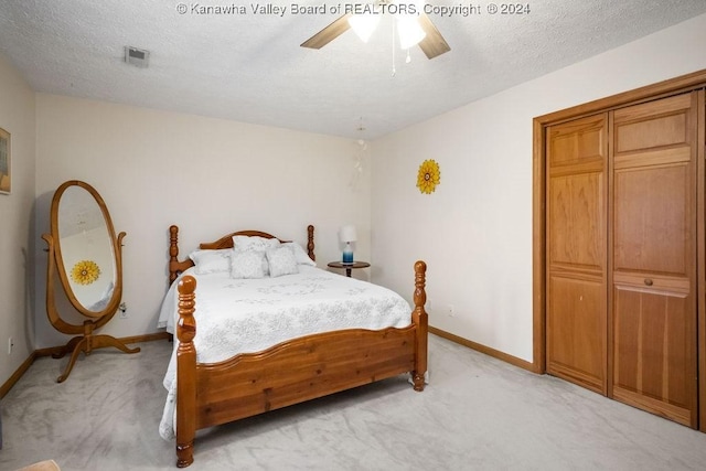 carpeted bedroom featuring ceiling fan and a textured ceiling