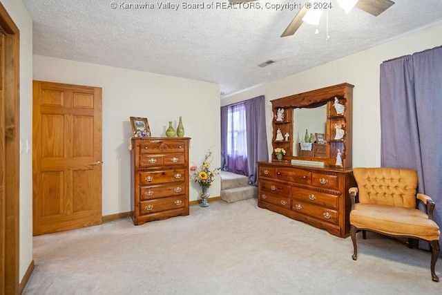 living area with ceiling fan, light colored carpet, and a textured ceiling