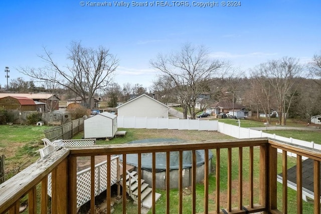 wooden terrace with a lawn, a covered pool, and a storage unit