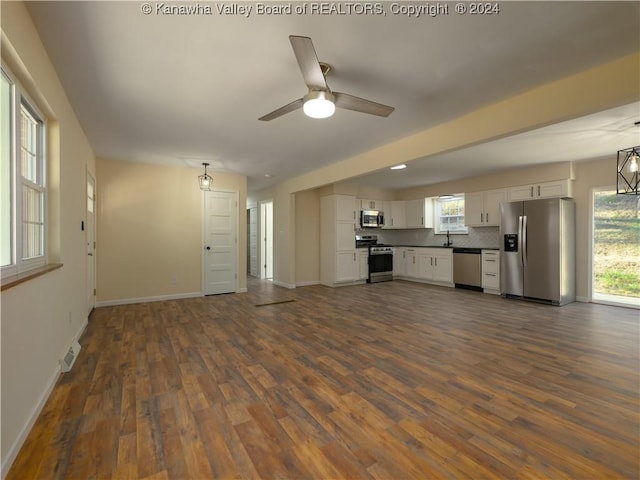 kitchen with white cabinetry, ceiling fan, appliances with stainless steel finishes, backsplash, and dark wood-type flooring