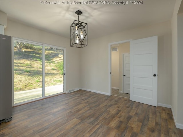 empty room with dark hardwood / wood-style flooring and an inviting chandelier