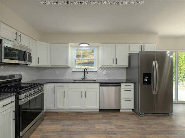 kitchen with appliances with stainless steel finishes, decorative backsplash, dark hardwood / wood-style floors, white cabinets, and sink