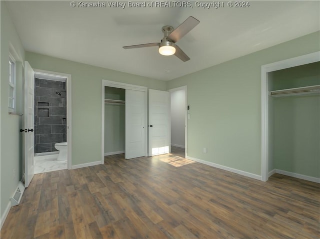 unfurnished bedroom with ceiling fan, dark hardwood / wood-style floors, ensuite bath, and multiple closets