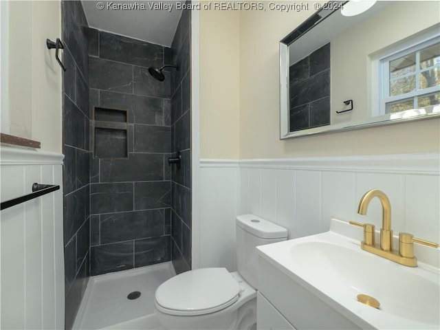 bathroom featuring toilet, a tile shower, and vanity