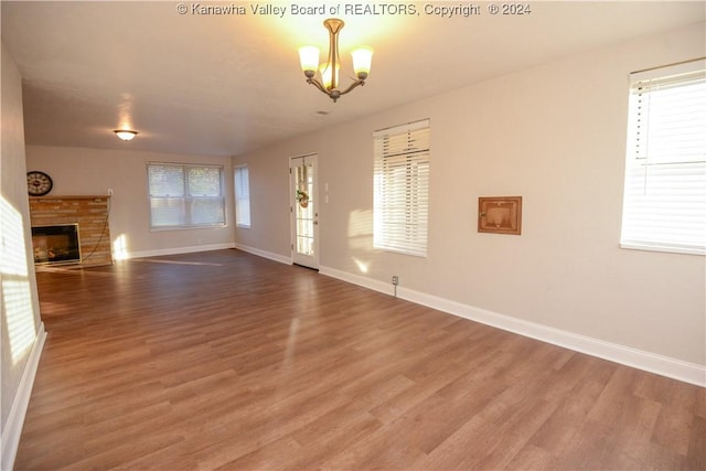 unfurnished living room featuring a wealth of natural light, a chandelier, and hardwood / wood-style flooring