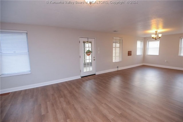 empty room with a notable chandelier and dark hardwood / wood-style floors