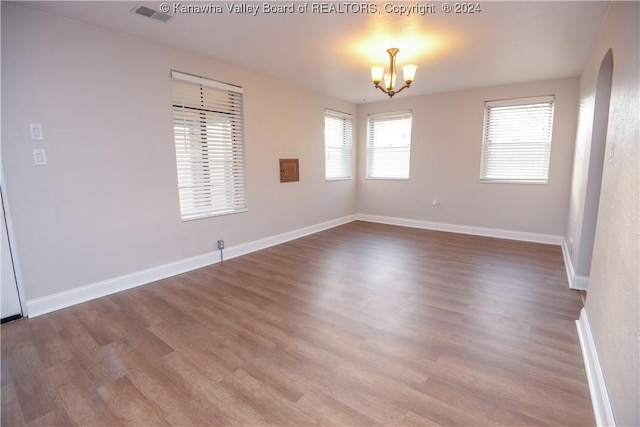 unfurnished room with wood-type flooring and an inviting chandelier