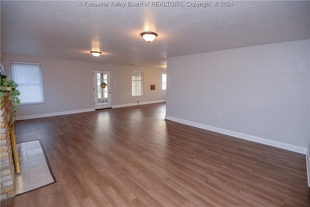 unfurnished living room featuring a textured ceiling, a stone fireplace, and dark hardwood / wood-style floors