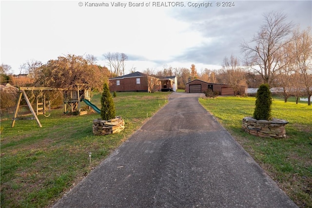 view of front of property with a playground, an outbuilding, a front lawn, and a garage