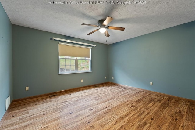 spare room featuring a textured ceiling, light wood-type flooring, and ceiling fan