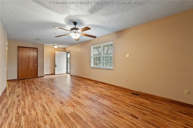 empty room featuring ceiling fan, light hardwood / wood-style floors, and a textured ceiling