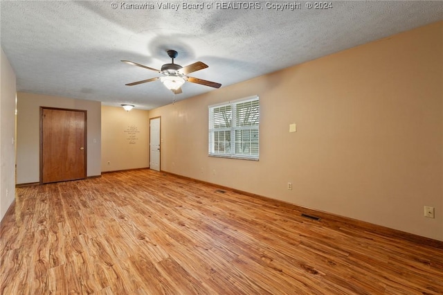 empty room featuring ceiling fan, a textured ceiling, and light hardwood / wood-style flooring