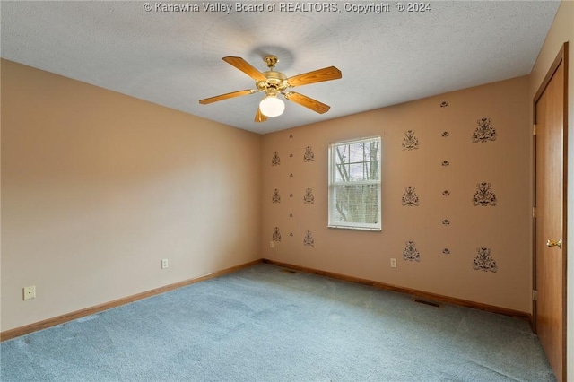 carpeted spare room with ceiling fan and a textured ceiling