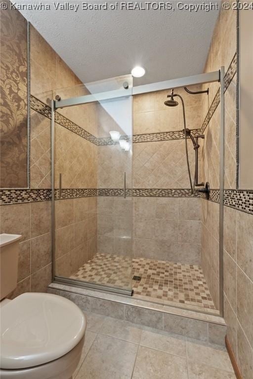 bathroom featuring tile patterned floors, a shower with door, and a textured ceiling