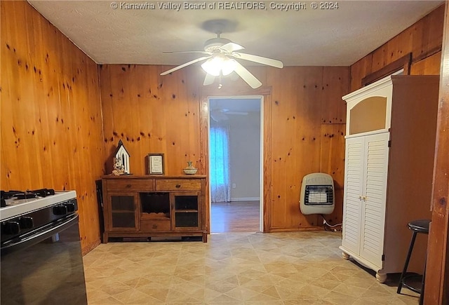 kitchen with wooden walls, gas range gas stove, and heating unit