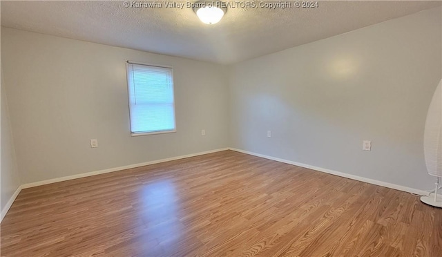 unfurnished room with a textured ceiling and light hardwood / wood-style flooring