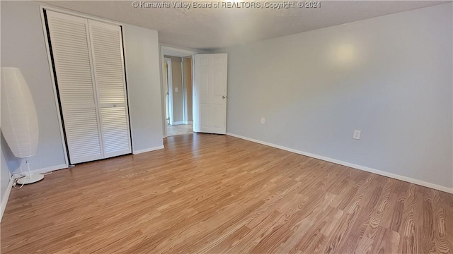 unfurnished bedroom with a textured ceiling, light hardwood / wood-style flooring, and a closet