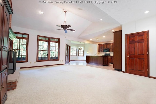 carpeted living room with ceiling fan with notable chandelier and lofted ceiling