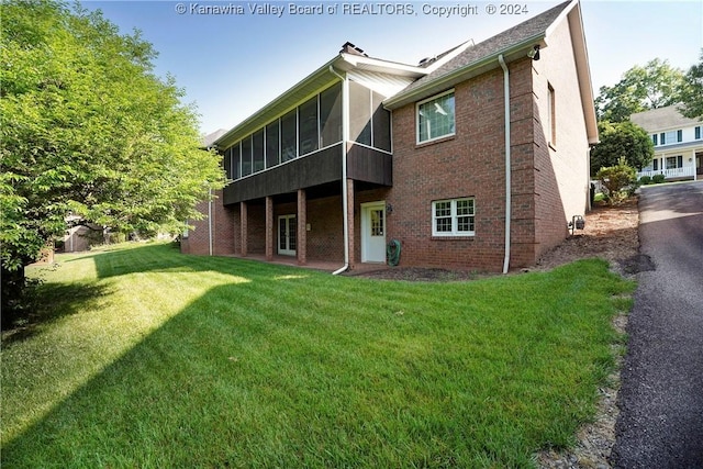 rear view of property featuring a sunroom and a yard