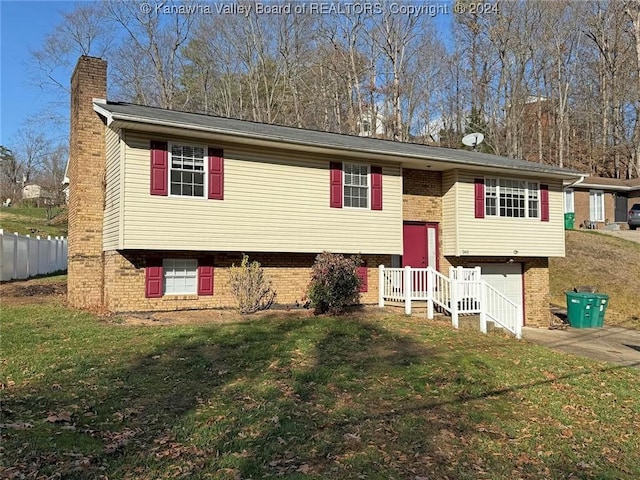 raised ranch featuring a garage and a front lawn