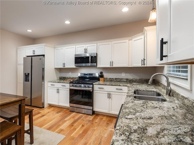 kitchen with light hardwood / wood-style floors, white cabinetry, sink, and appliances with stainless steel finishes