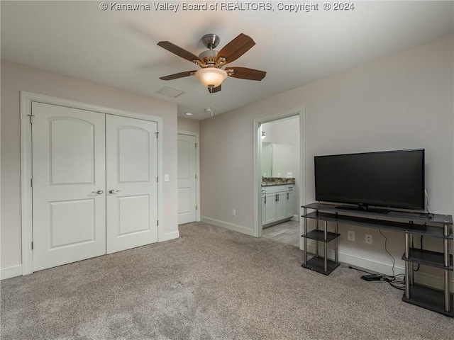 carpeted bedroom with ensuite bath, ceiling fan, and a closet