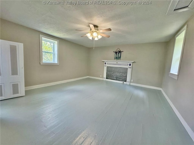 unfurnished living room featuring a fireplace, ceiling fan, hardwood / wood-style floors, and a textured ceiling