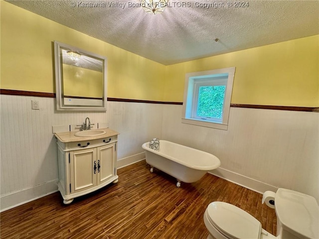 bathroom featuring vanity, wood-type flooring, a textured ceiling, and a tub to relax in