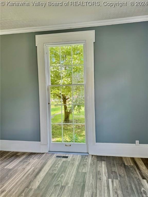 doorway to outside featuring hardwood / wood-style flooring and ornamental molding