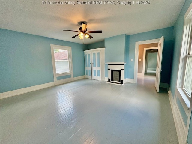 unfurnished living room featuring a textured ceiling, light wood-type flooring, and ceiling fan