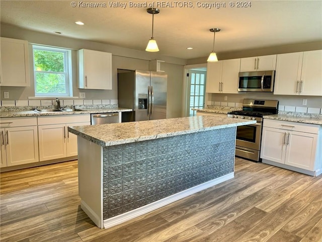 kitchen featuring pendant lighting, stainless steel appliances, white cabinetry, and sink