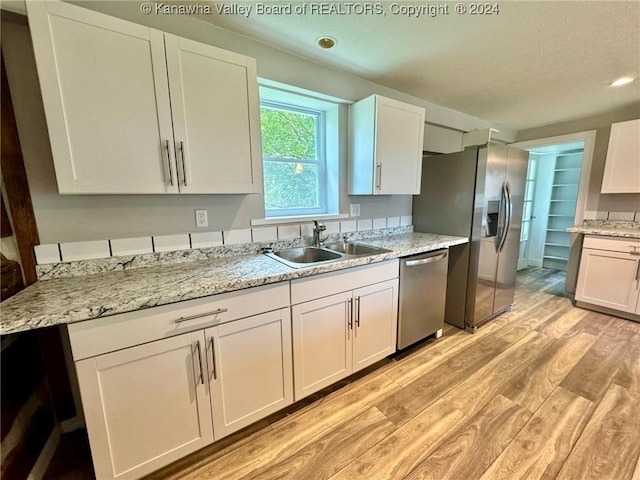 kitchen featuring white cabinets, appliances with stainless steel finishes, light hardwood / wood-style floors, and sink