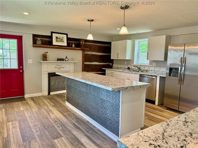 kitchen with a center island, white cabinets, stainless steel appliances, and decorative light fixtures