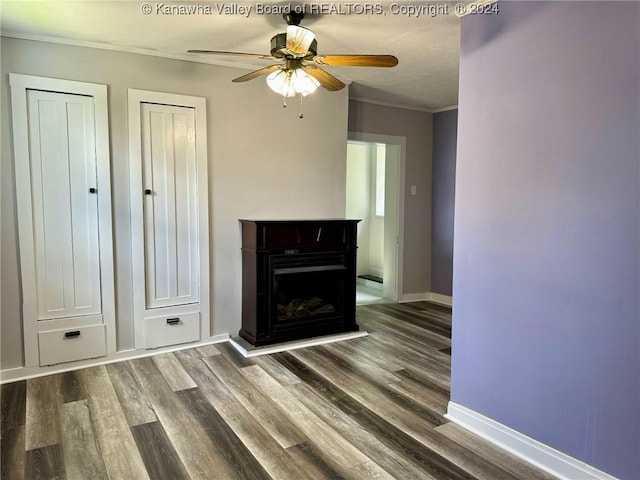 unfurnished living room with ceiling fan, crown molding, and dark wood-type flooring